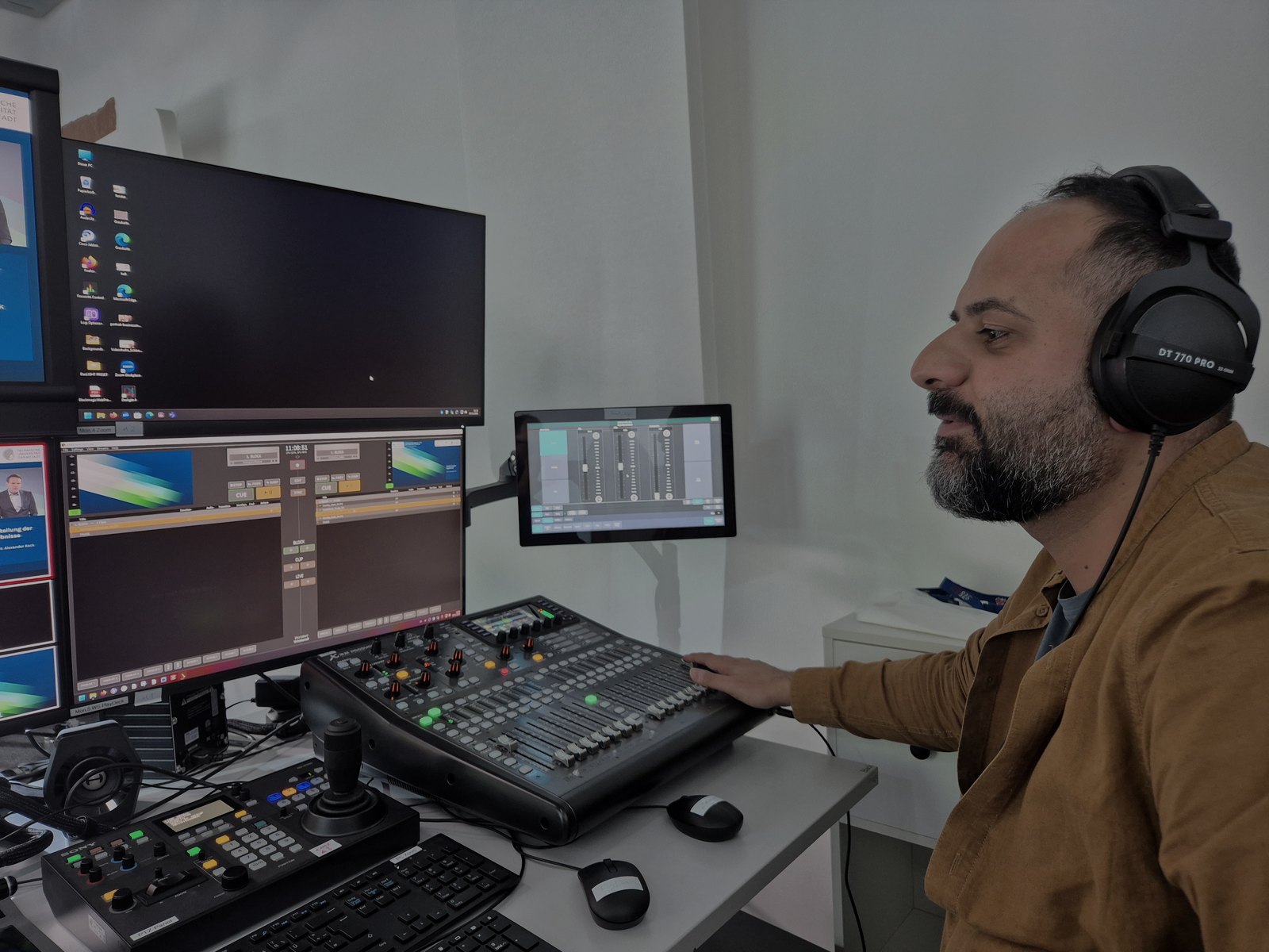 Mostafa at a hybrid production desk with screens, audio controls, and live event equipment